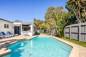 A rectangular swimming pool with clear blue water, surrounded by a patio with lounge chairs and a covered seating area. - Outdoor Paradise  Heated Pool near Beach 4/3 (Fort Lauderdale)