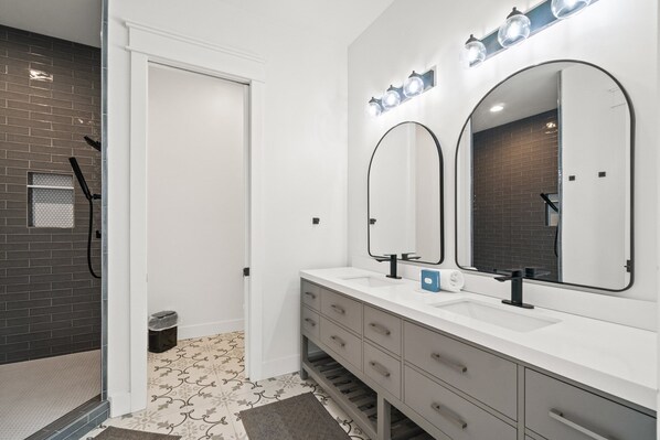 A modern bathroom with a white vanity, two large mirrors, and a shower area with a glass door. - Maison Bleu: Beautiful Beach Views, Private Pool, Pet Friendly, East End (St. George Island)