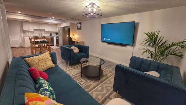 Una sala de estar moderna con un sofá, sillones, una mesa de centro y un televisor.