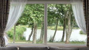 A room with a large window overlooking a lake and trees.