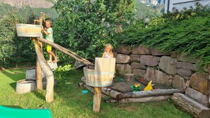 A wooden play structure with a rope ladder and a stone wall in the background. - JAZZ quiet, cozy apartment with sunrise view. 10min from Lake Kaltern (Auer)