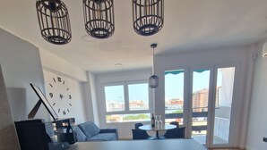 Une cuisine compacte dotée d’un lave-linge et d’un sèche-linge intégrés, un coin repas avec une table ronde et une grande fenêtre offrant une vue sur la ville.