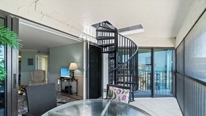 Un interior moderno con una mesa de vidrio, una escalera en espiral y vistas a través de puertas de cristal.