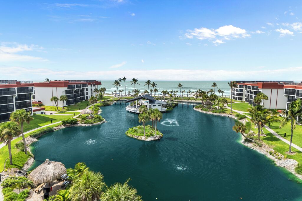 Un resort con un elemento acuático central, palmeras y vista al océano.