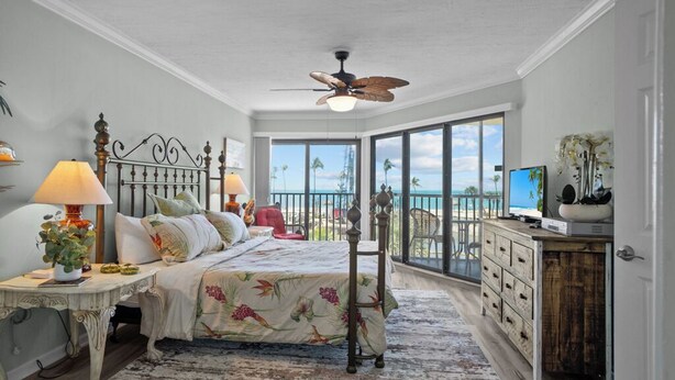 A bedroom with a bed, bedside tables, a dresser, and a balcony with a view of the ocean. - 3rd-Floor Island Getaway w/ Lagoon Views – Walk to the Beach! (Sanibel)