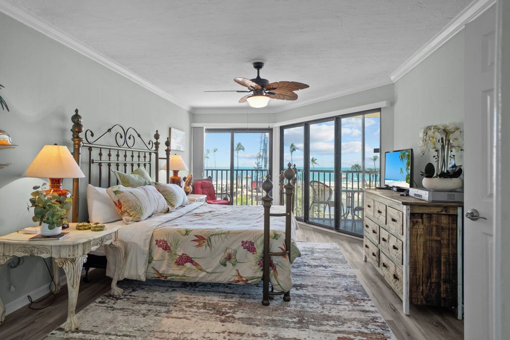 Une chambre à coucher comprenant un lit, des tables de chevet, une commode et un balcon avec vue sur l’océan.