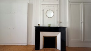 A room with a fireplace, a mirror, and a door. - Charming bright studio (La Rochelle)