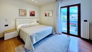 Een slaapkamer met een bed, een nachtkastje, een raam met uitzicht en een radiator.