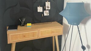 Een houten bureau met een prikbord, een lamp en een notitieboekje.