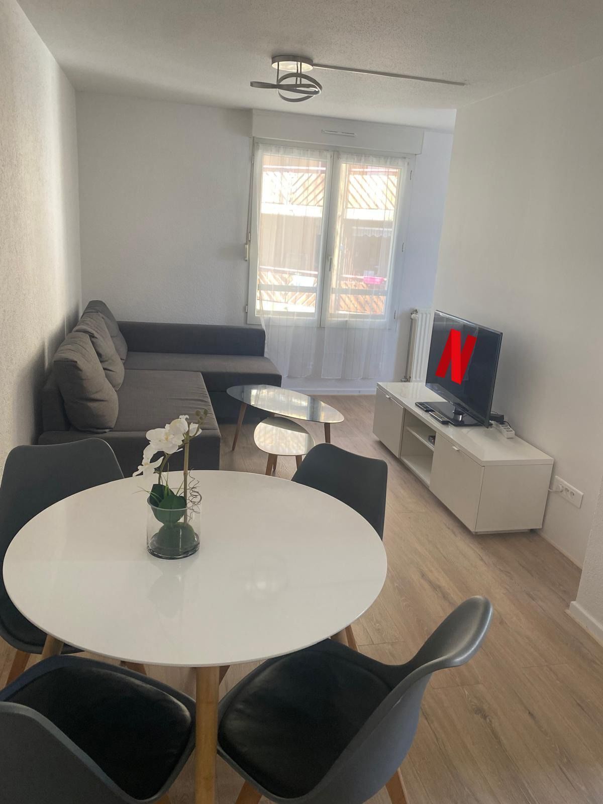 Un salon moderne avec un canapé, une table à manger et des chaises, un téléviseur et un balcon avec vue.