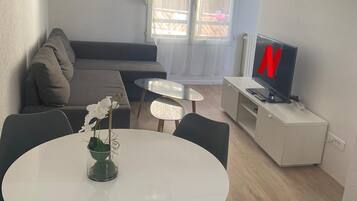 Un salon moderne avec un canapé, une table à manger et des chaises, un téléviseur et un balcon avec vue.