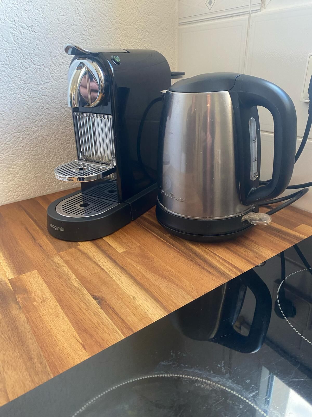 Une machine à café et une bouilloire sur un plan de travail en bois.