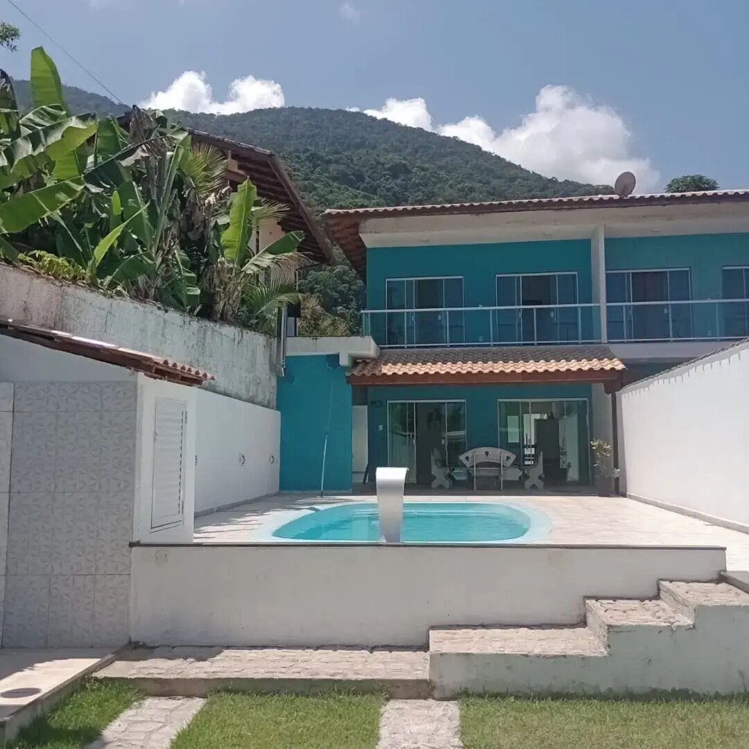 Ein zweistöckiges Haus mit Swimmingpool, einer überdachten Terrasse und einem Berg im Hintergrund.
