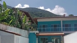 A two-story house with a swimming pool, a covered patio, and a mountain in the background.