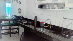 A modern kitchen with dark cabinetry, a granite countertop, and stainless steel appliances.