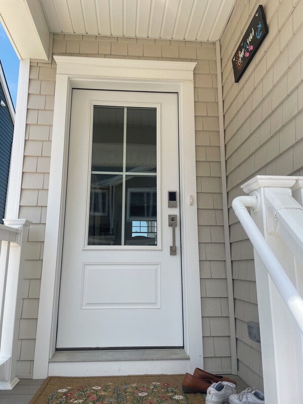 A white front door with a glass panel, a small porch area with a doormat, and a mailbox on the right.