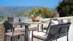 An outdoor dining area with a table set for two, surrounded by chairs with cushions. - Evergreen villa, private pool, a peaceful Cretan retreat (Amari)