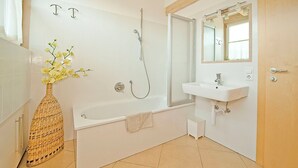 A modern bathroom with a bathtub, a white sink, and a large mirror. - PINK LADY family-friendly vacation home, 10 minutes from Lake Kaltern (Auer)
