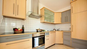 A modern kitchen with wooden cabinets, a stainless steel oven, and a glass-fronted upper cabinet. - PINK LADY family-friendly vacation home, 10 minutes from Lake Kaltern (Auer)