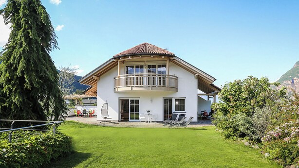 A two-story house with a balcony, a lawn, and mountains in the background. - PINK LADY family-friendly vacation home, 10 minutes from Lake Kaltern (Auer)