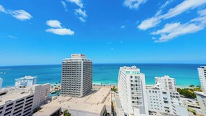 A high-rise hotel with a view of the ocean, multiple balconies, and a clear sky. - Deluxe Ocean View Studio with Free Parking & Pool (San Juan)