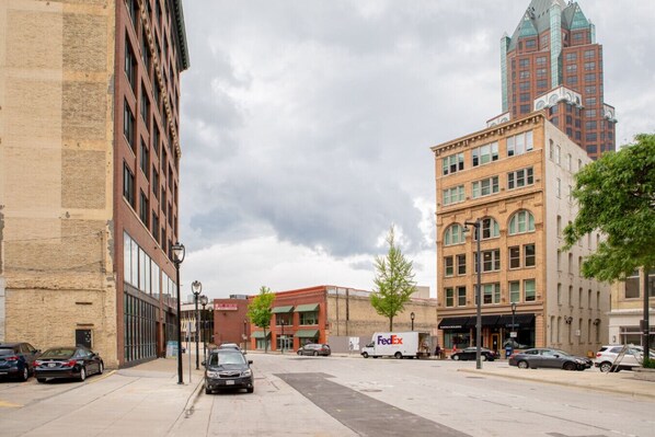 A street view with a mix of historic and modern buildings, a FedEx delivery truck, and parked cars.