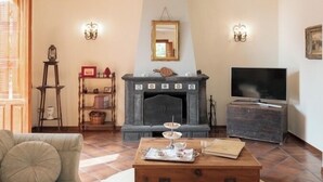 Una sala de estar con chimenea, un sofá, una mesa de centro y un televisor.