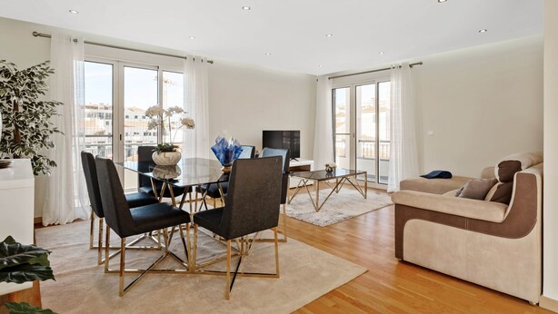 A spacious living area with a dining table, chairs, a sofa, and a TV.
