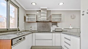 A modern kitchen with white cabinets, granite countertops, a built-in dishwasher, and a window providing a view of the outside.