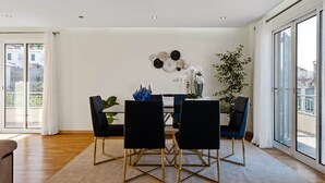 A modern dining area with a white table, black chairs, and a decorative wall.