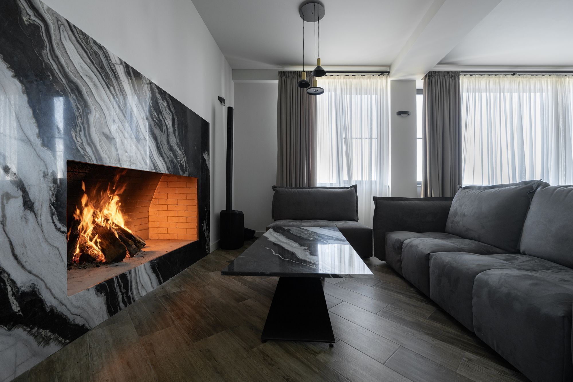 Una sala de estar moderna con una chimenea de mármol, un sofá y una mesa de centro.
