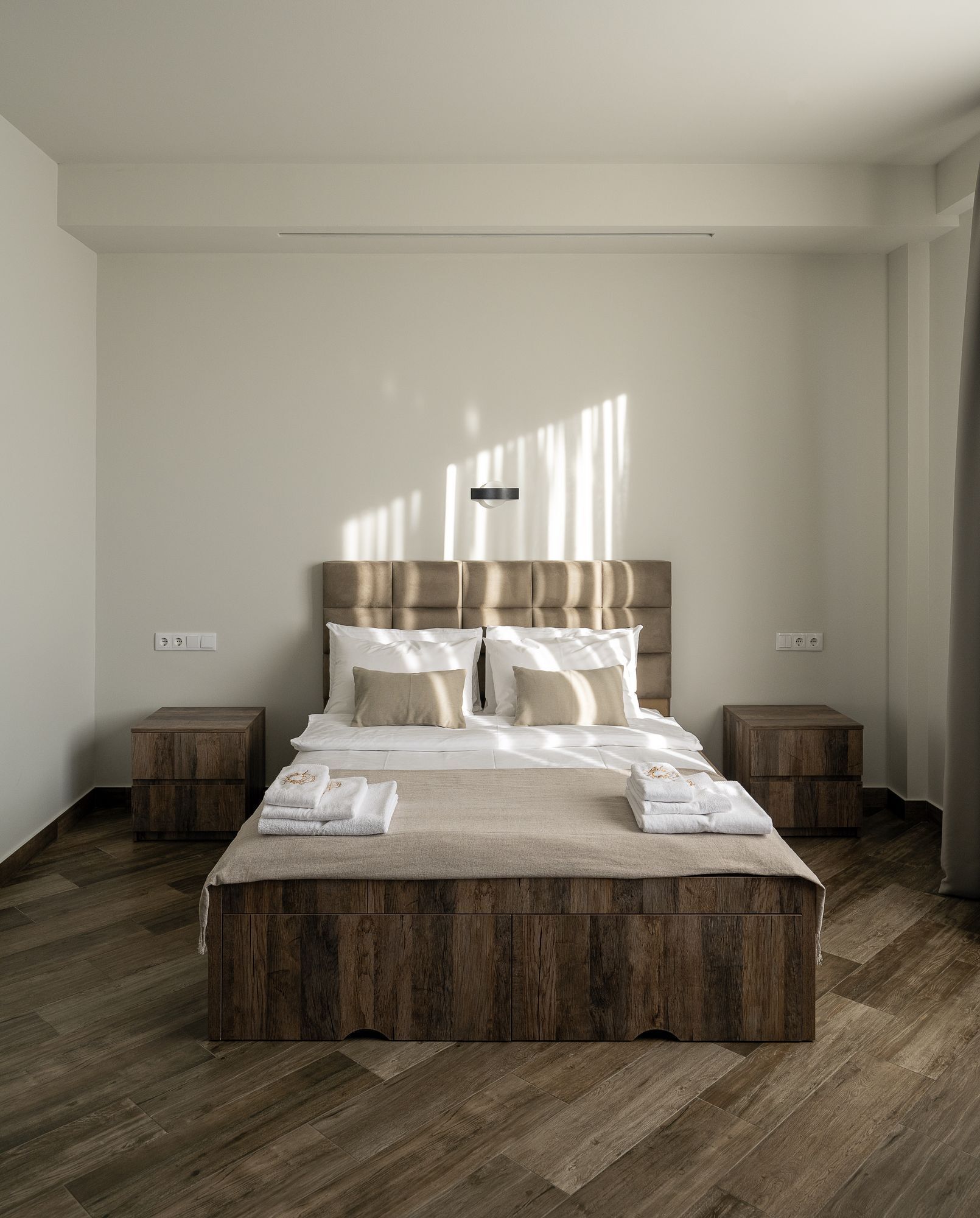 A modern bedroom with a wooden bed, two bedside tables, and a nightstand.