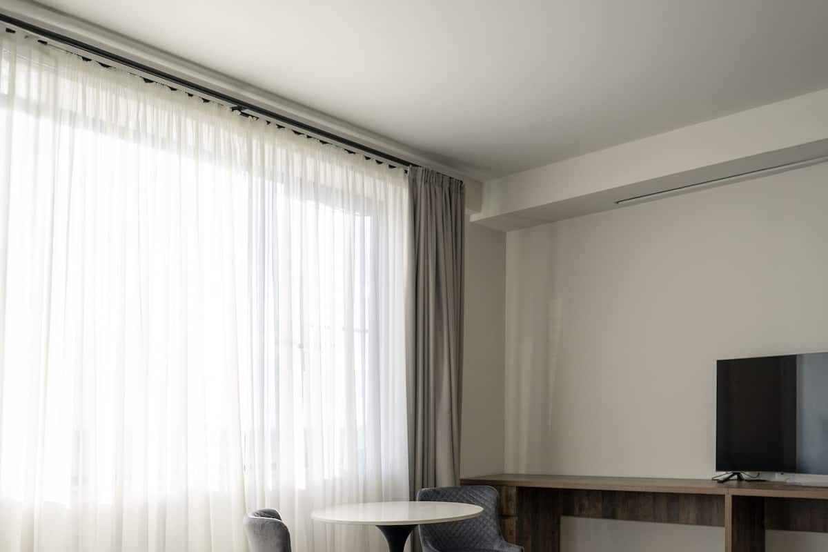 Quarto de hotel com uma cama, uma mesa de trabalho com televisão, duas cadeiras e uma pequena mesa.