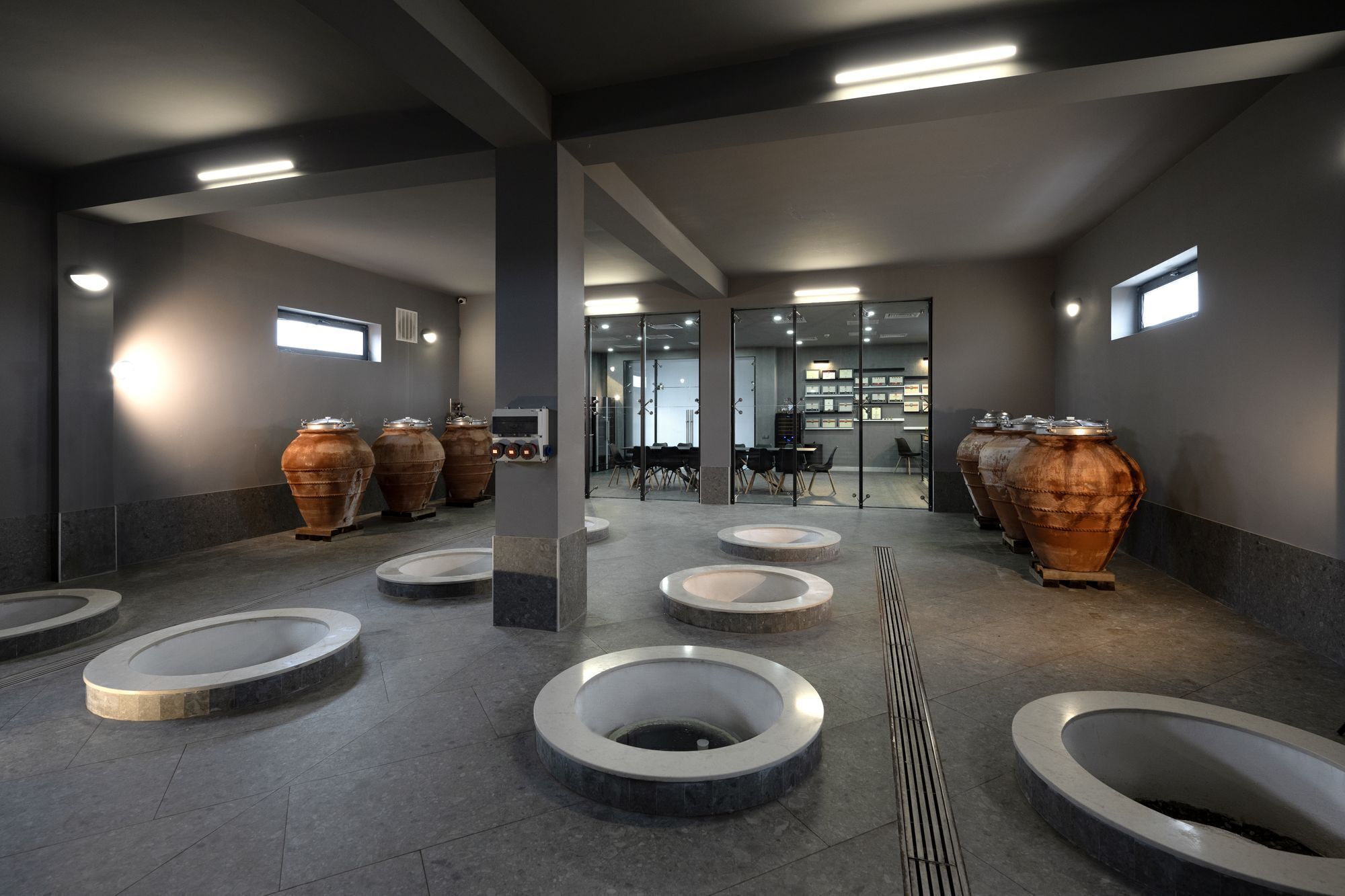 A modern restroom with multiple urinals, large copper pots, and a central seating area.