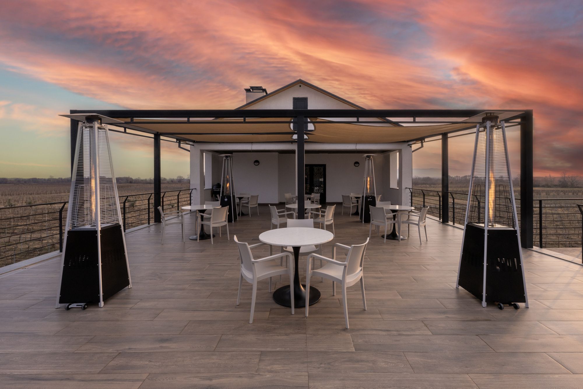 Un patio al aire libre con mesas y sillas, una zona cubierta y vistas al paisaje.