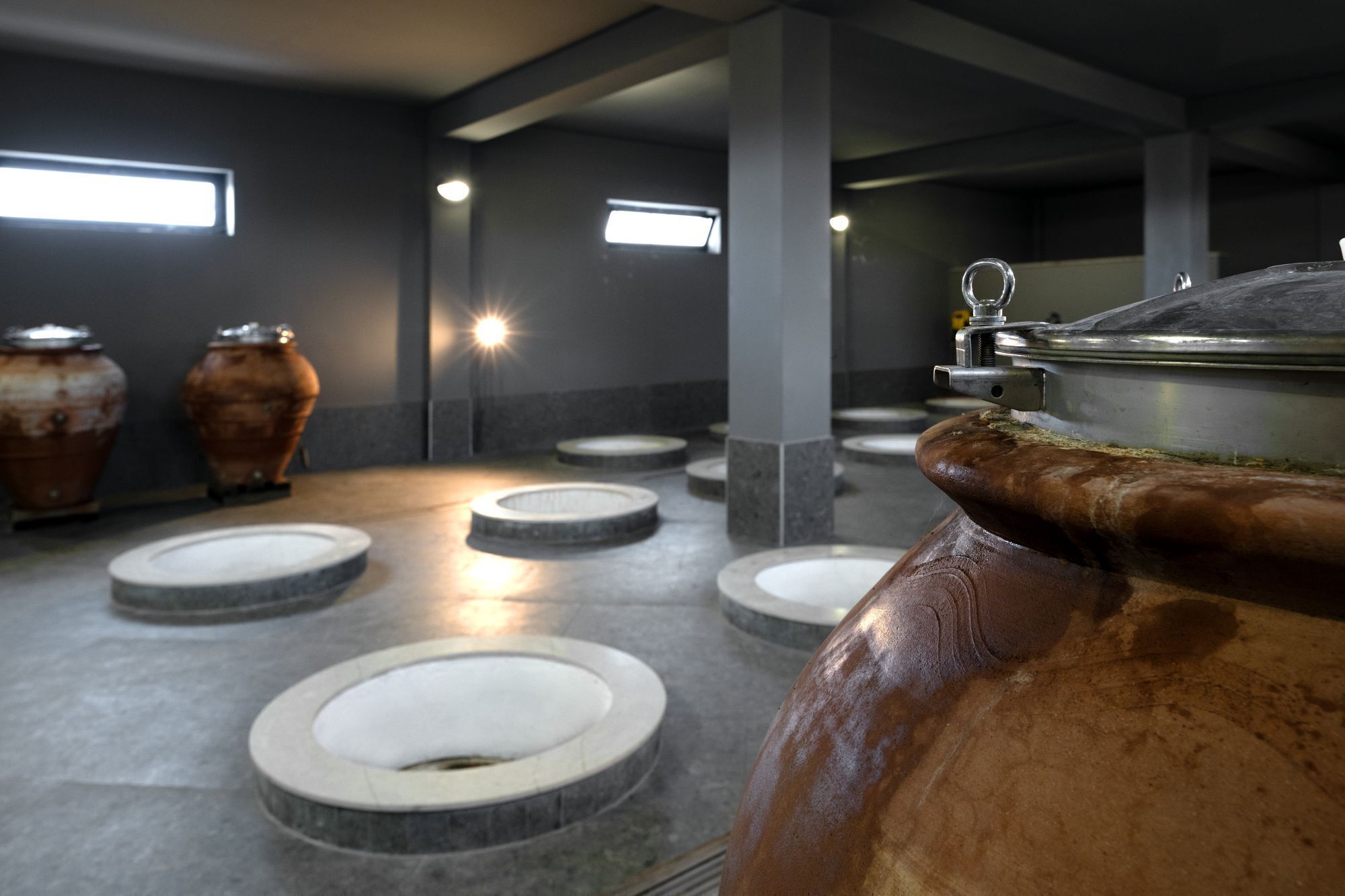 A restroom with multiple urinals and a large ceramic pot.