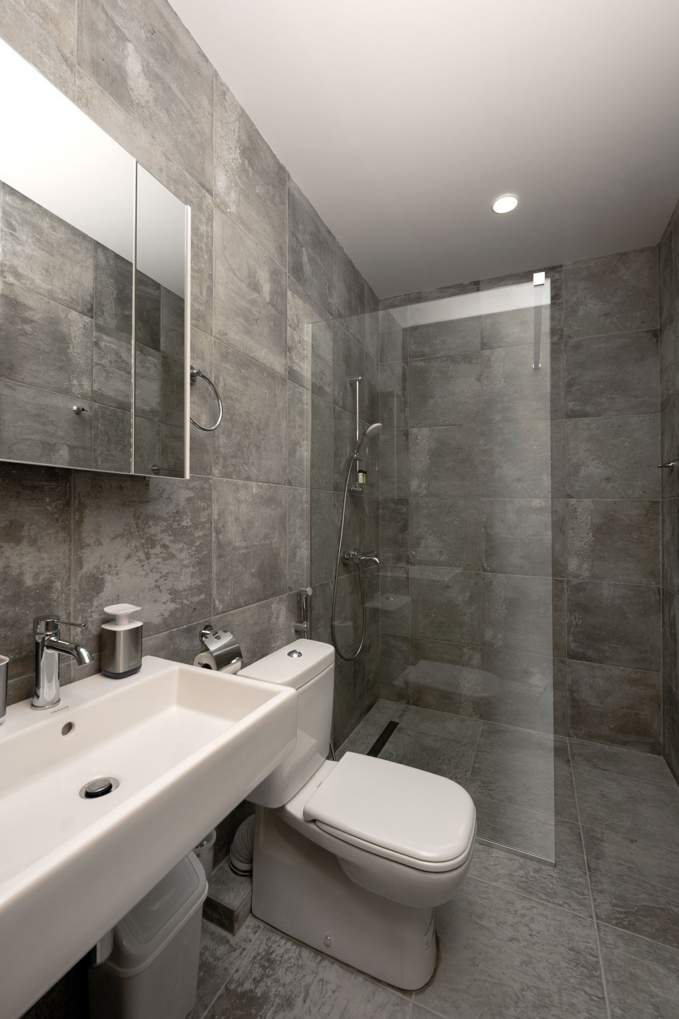 A modern bathroom with a large sink, mirror, and toilet.