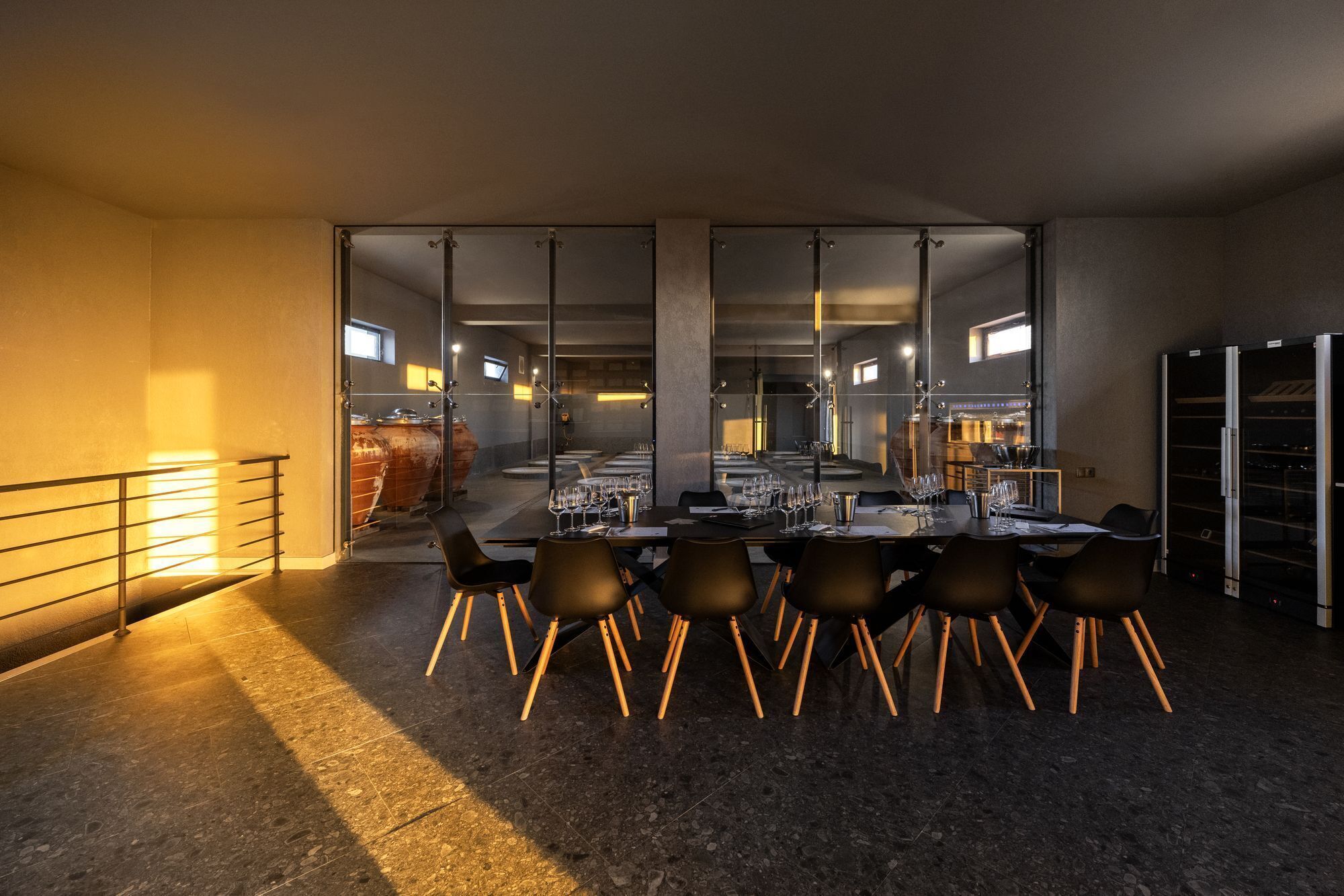 A modern dining area with a long table set for a meal, surrounded by chairs with wooden legs.
