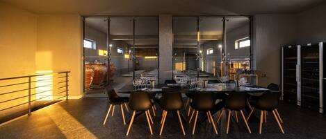 A modern dining area with a long table set for a meal, surrounded by chairs with wooden legs.