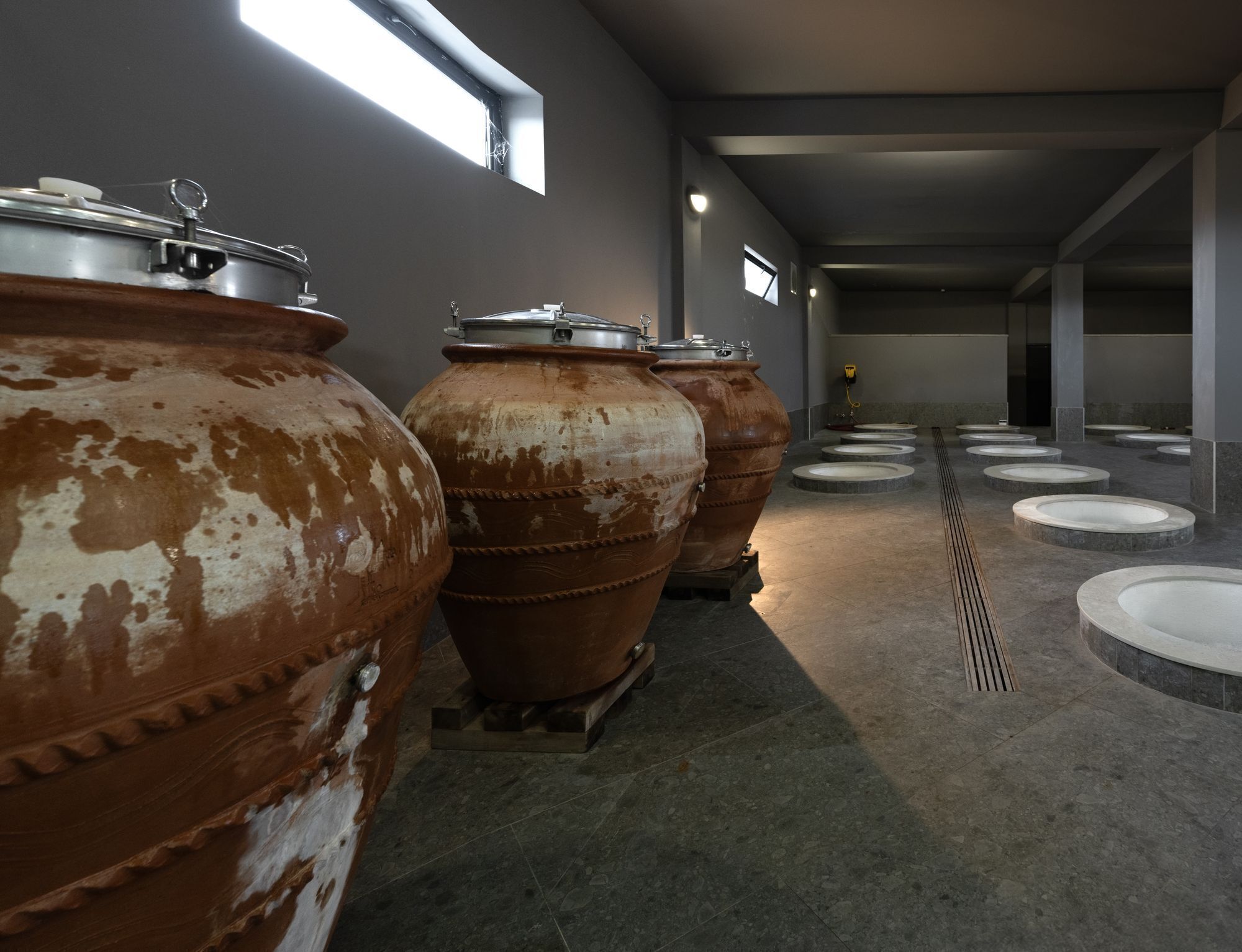 A corridor with large industrial tanks and multiple sinks.