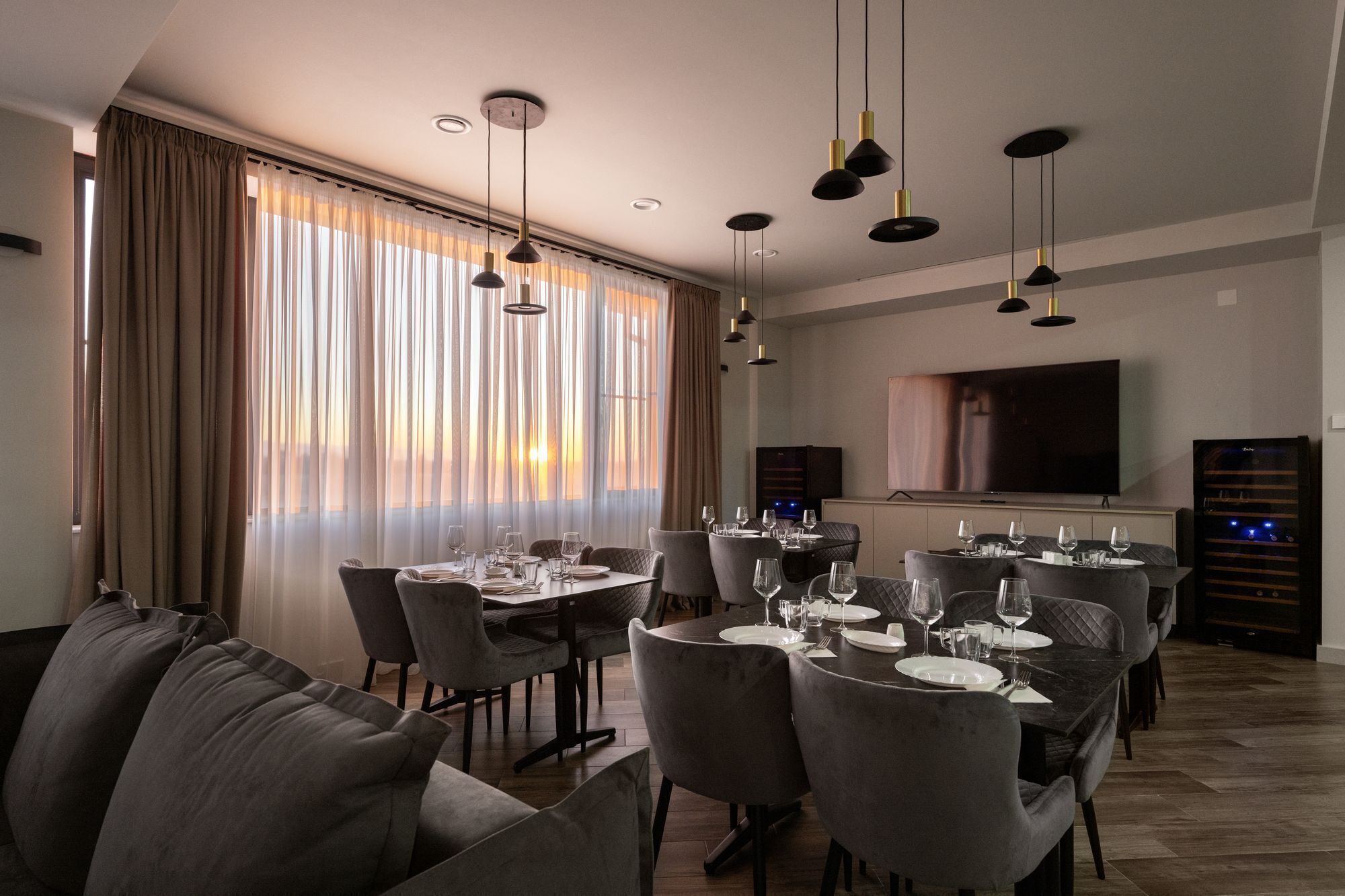 A dining area with a long table set for a meal, surrounded by cushioned chairs.