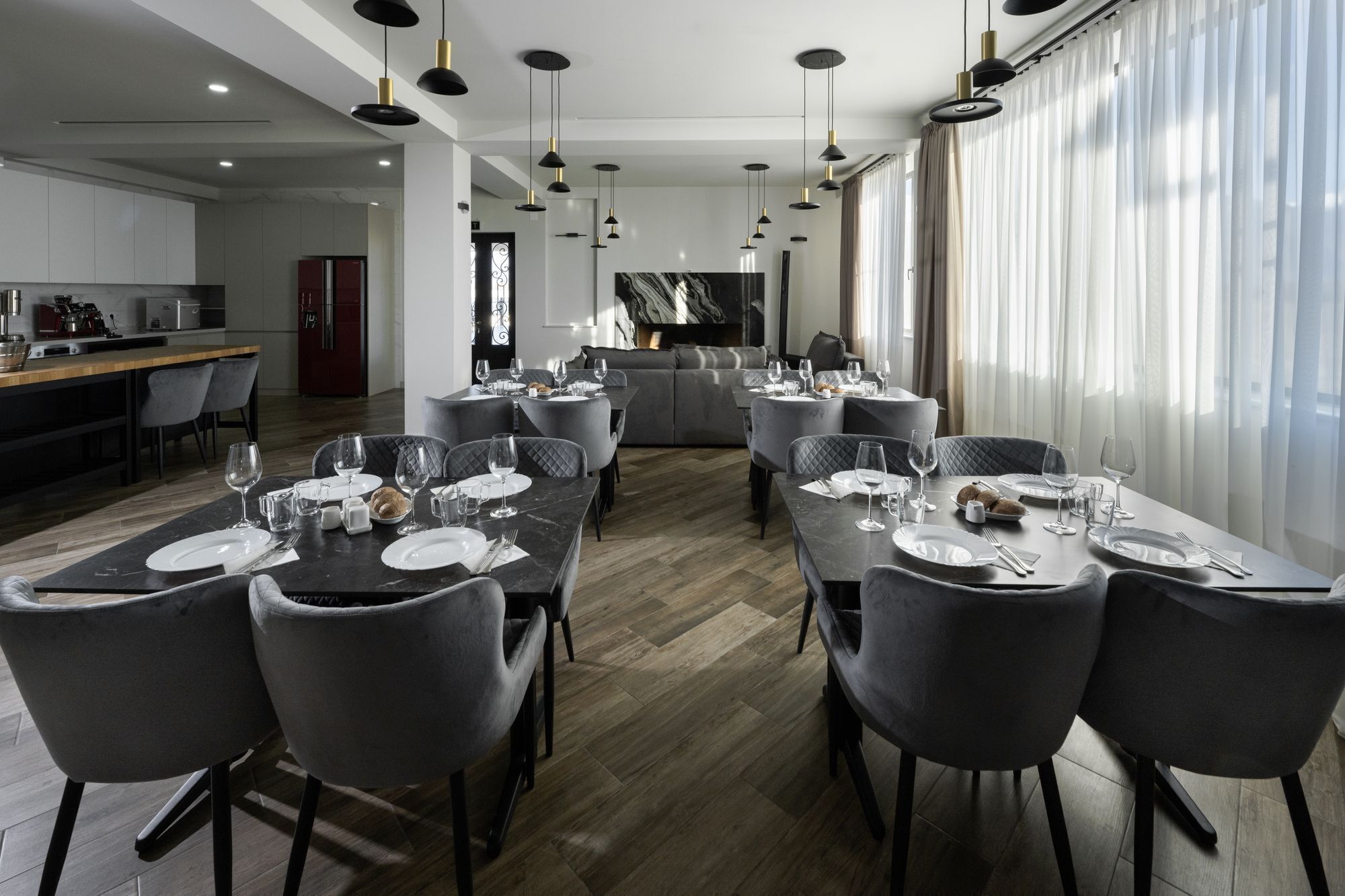 A modern dining area with a long table set for a meal, surrounded by grey upholstered chairs.