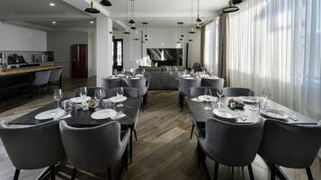 A modern dining area with a long table set for a meal, surrounded by grey upholstered chairs.