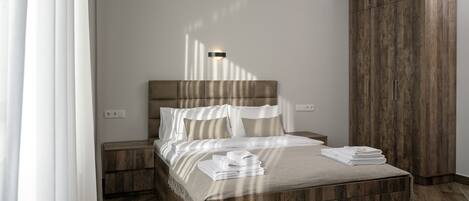 A modern bedroom with a wooden headboard, a bedside table, and a large wooden wardrobe.