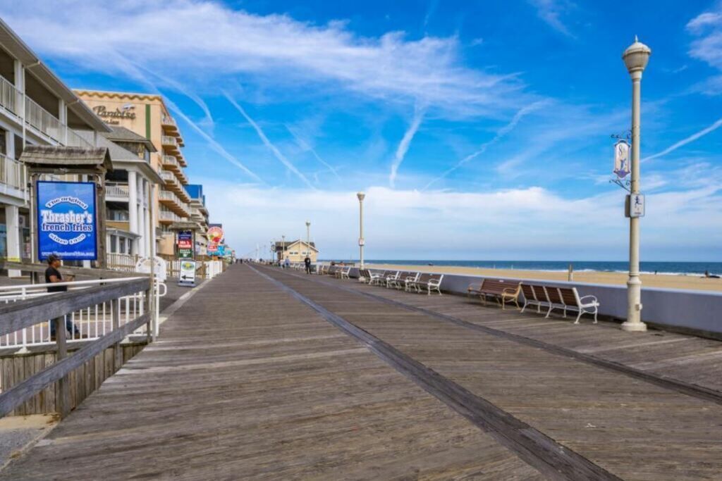 Ein Promenadendeck mit einem Strand im Hintergrund, einem Schild für 'Thrasher's French Fries' und einem Laternenpfahl.
