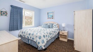A bedroom with a bed, a nightstand, a wardrobe, and a window with curtains.