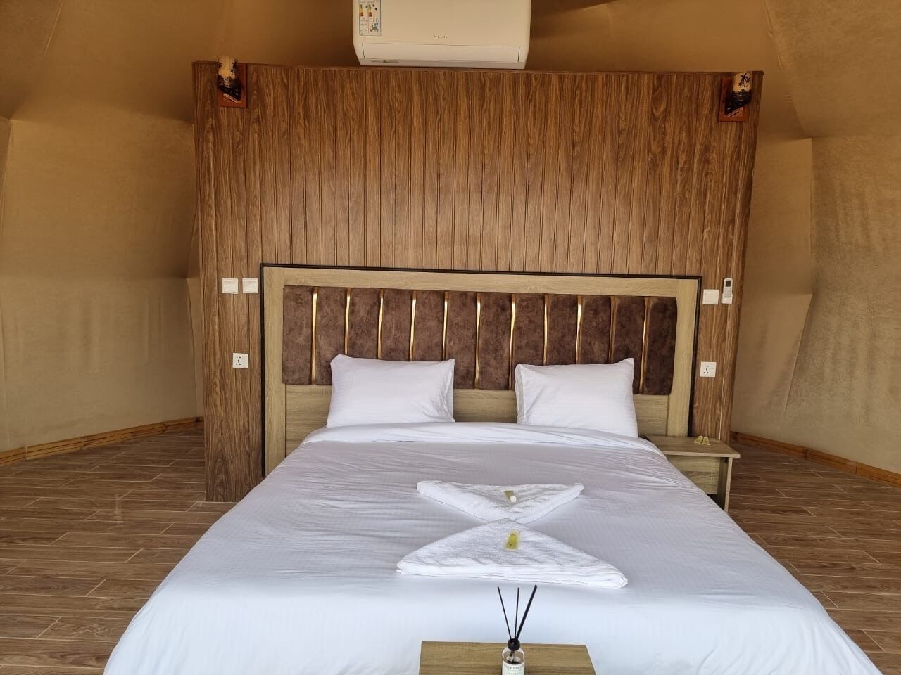 Hotellihuone, jossa on suuri sänky, puinen pääty ja puulattia.
