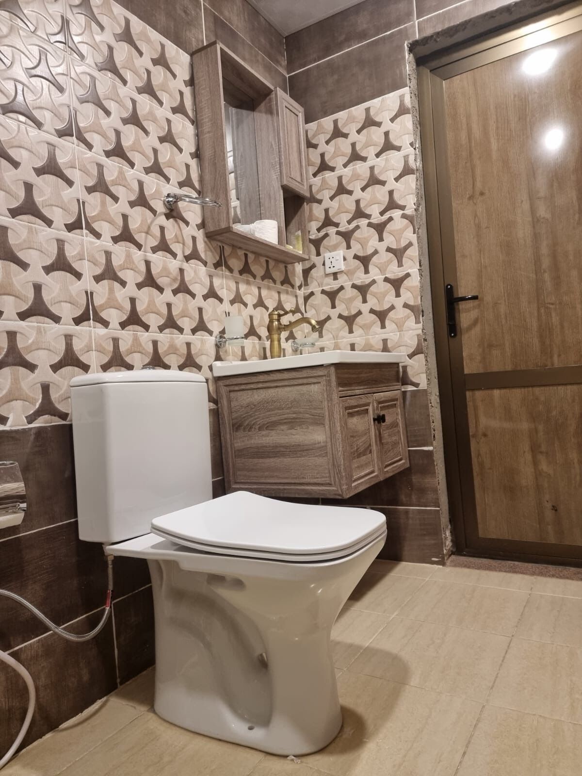 A bathroom with a white toilet, wooden cabinets, and patterned wall tiles.