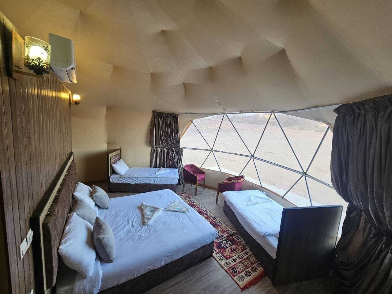 A cozy room with two beds, a small table, and a window with curtains.