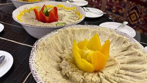 A dining table with various dishes, including a central dish with a yellow flower decoration. - Wadi Rum Desert Camp (Wadi Rum)